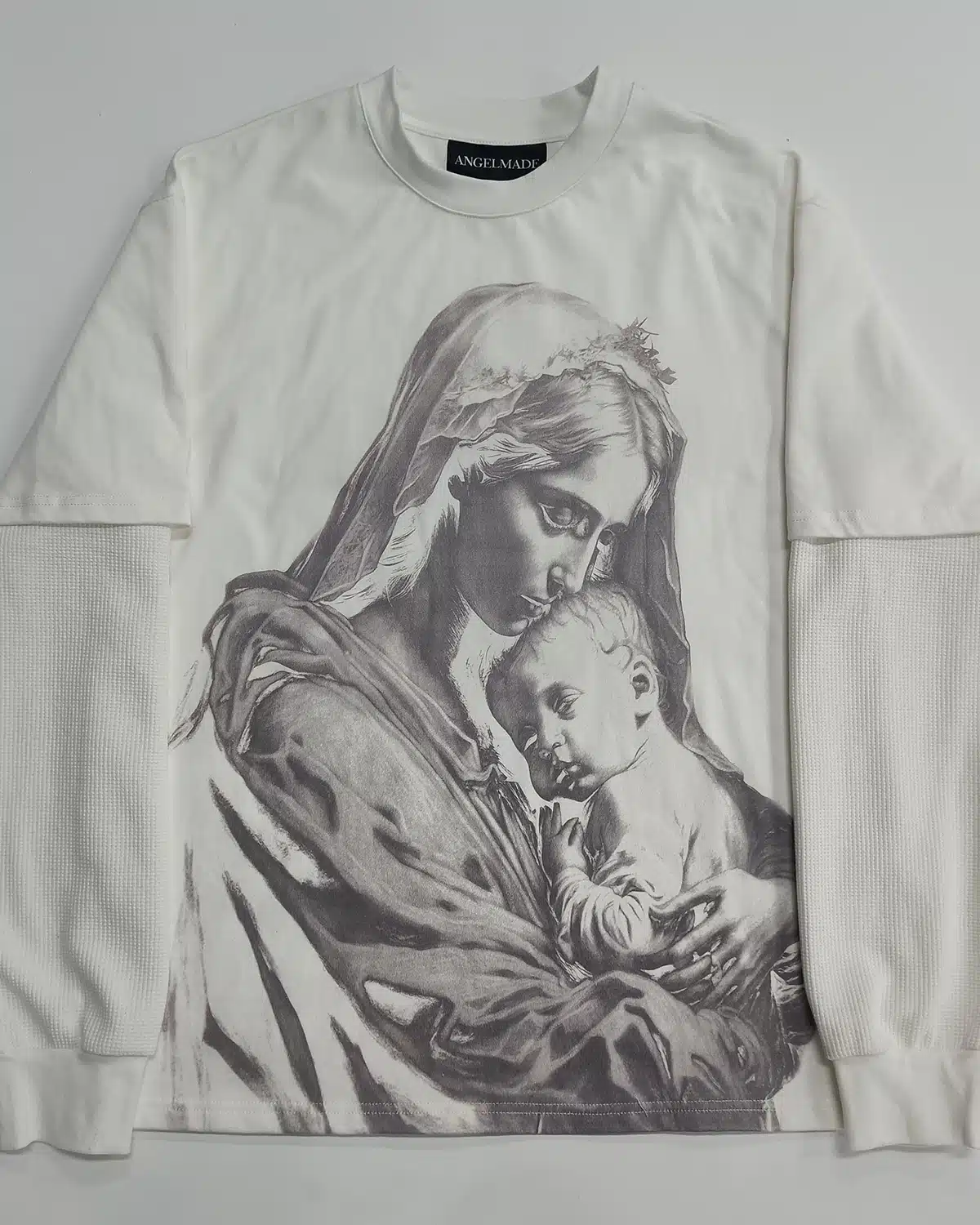 White layered graphic top with printed artwork and contrasting long sleeves