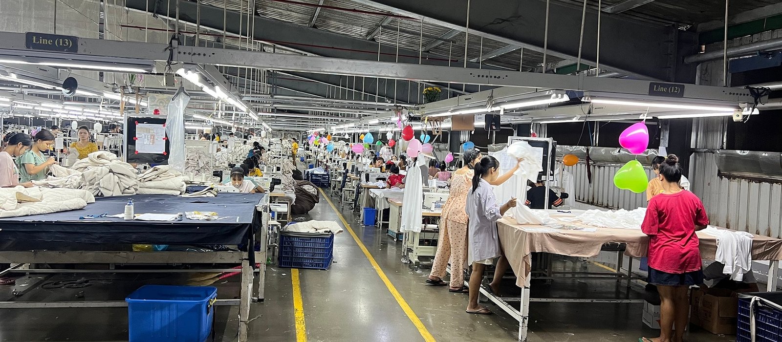 Garment workers sewing and handling apparel across multiple production lines in a clothing factory