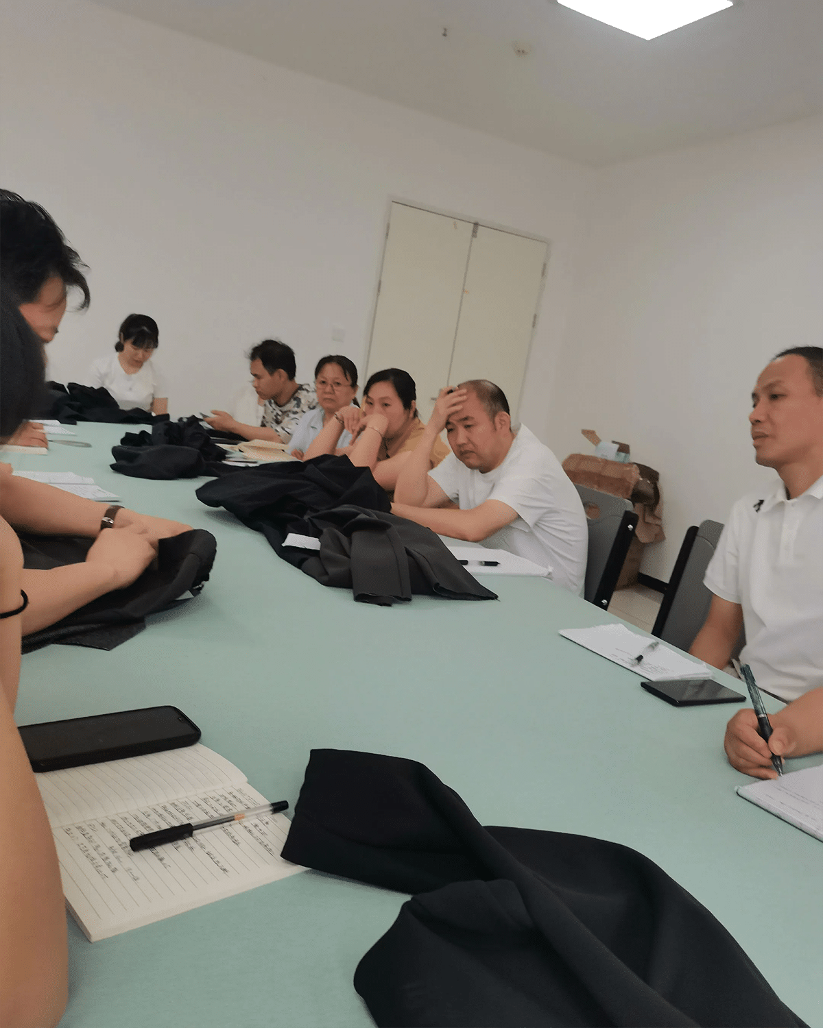 Apparel manufacturing team reviewing garment samples and production notes during a development meeting