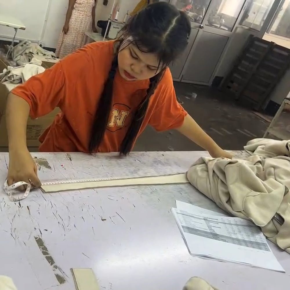 Garment worker measuring apparel at a worktable during in-line production inspection
